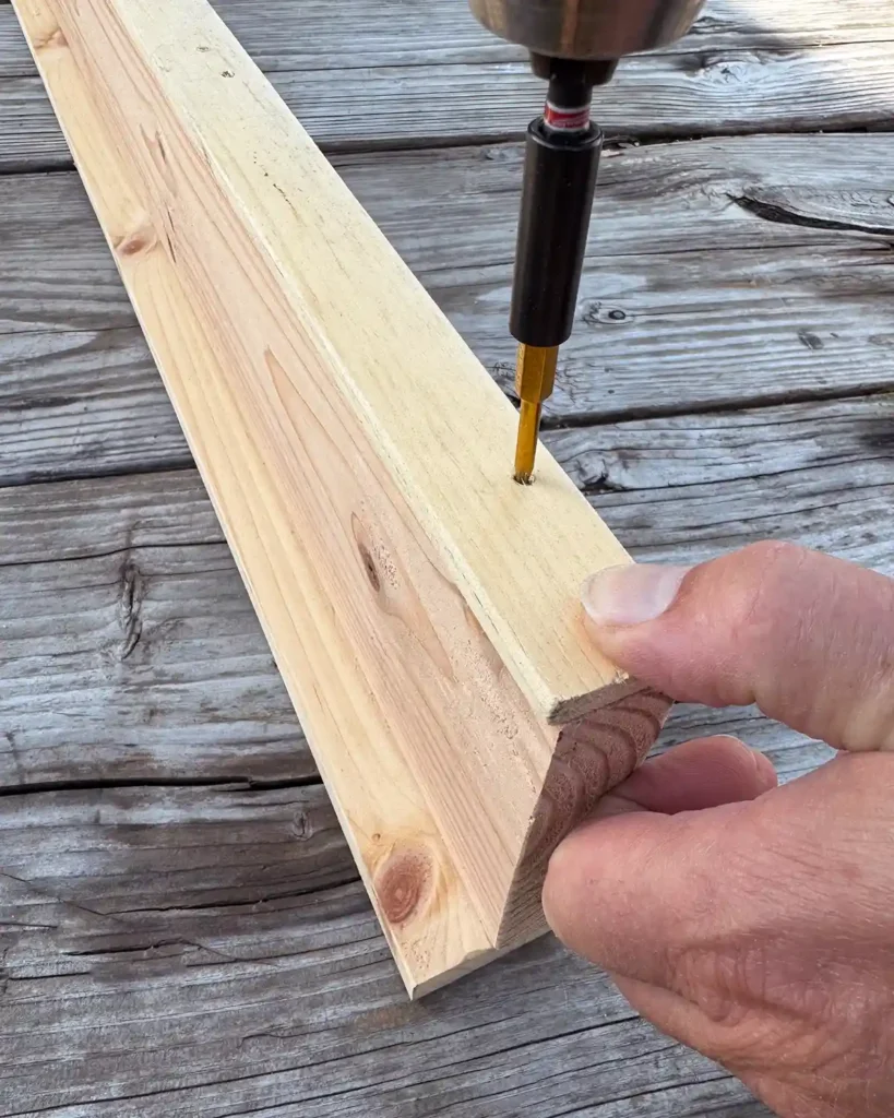 Using a cordless drill to screw together the wooden components of a DIY ledge shelf